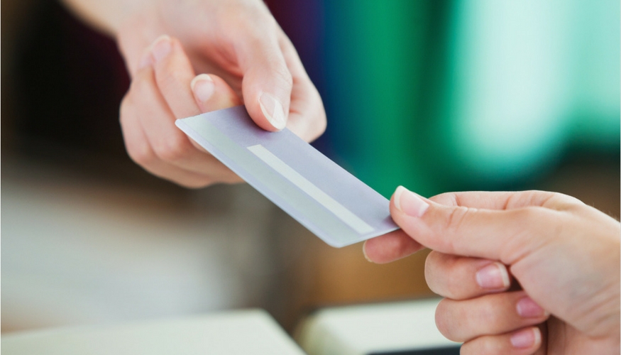 two hands handing a card as payment